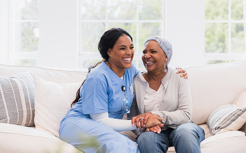 Senior woman and her adult daughter sitting on a sofa hugging each other and smiling