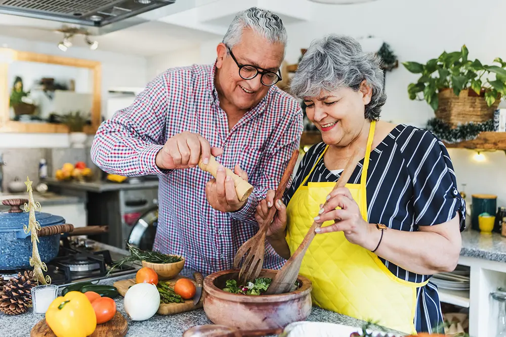 Senior couple preparing a salad in their apartment